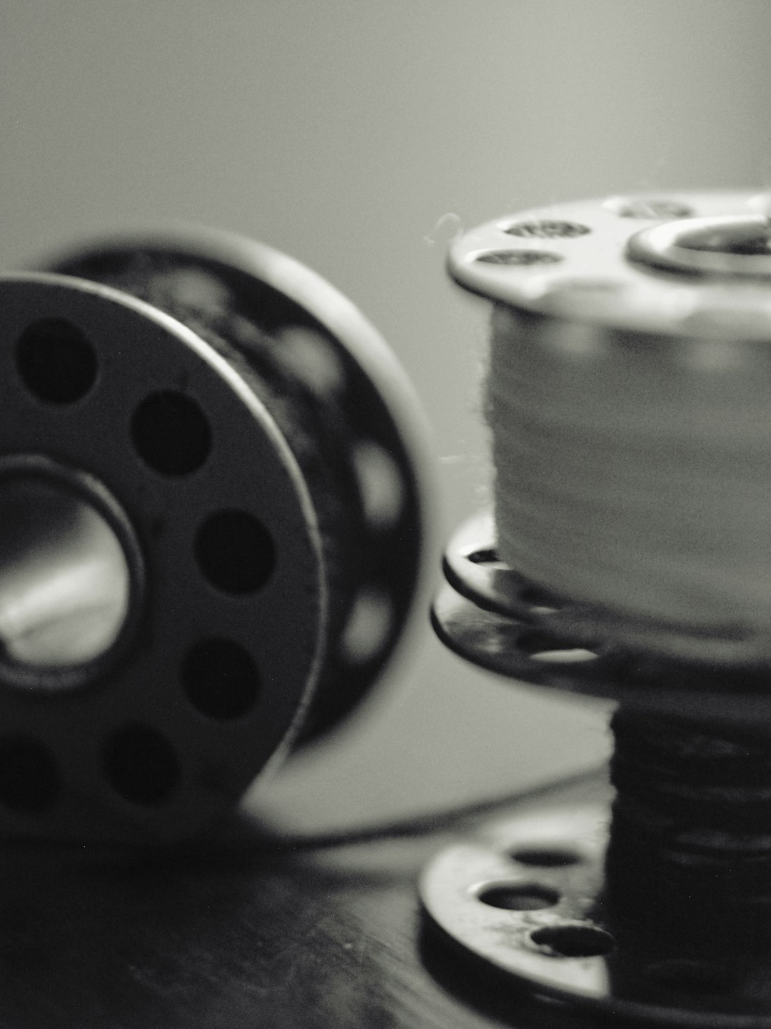 two-sewing-bobbins-one-with-thread-in-black-and-white-ise2njjafjc